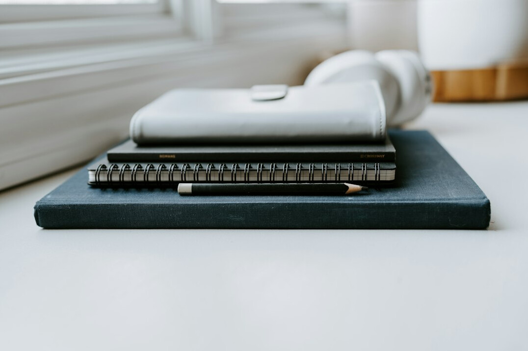 Hands writing on a notebook next to a calculator and financial documents